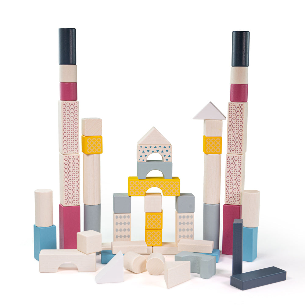 Front view of Drum of 50 Bricks showcasing colorful patterned wooden shapes arranged as towers and arches on a white background