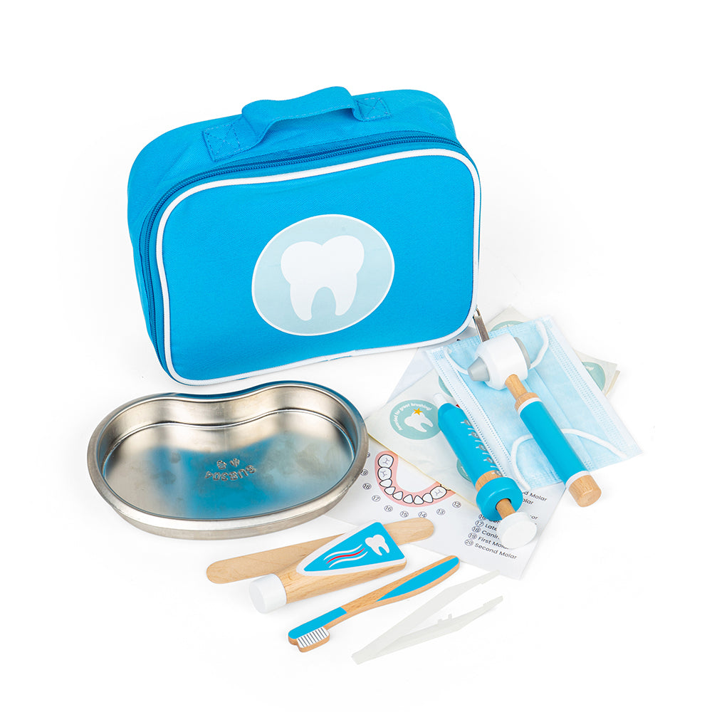 Angled view of wooden dentist play set with blue carry bag, metal tray, toothbrush and syringe on white background