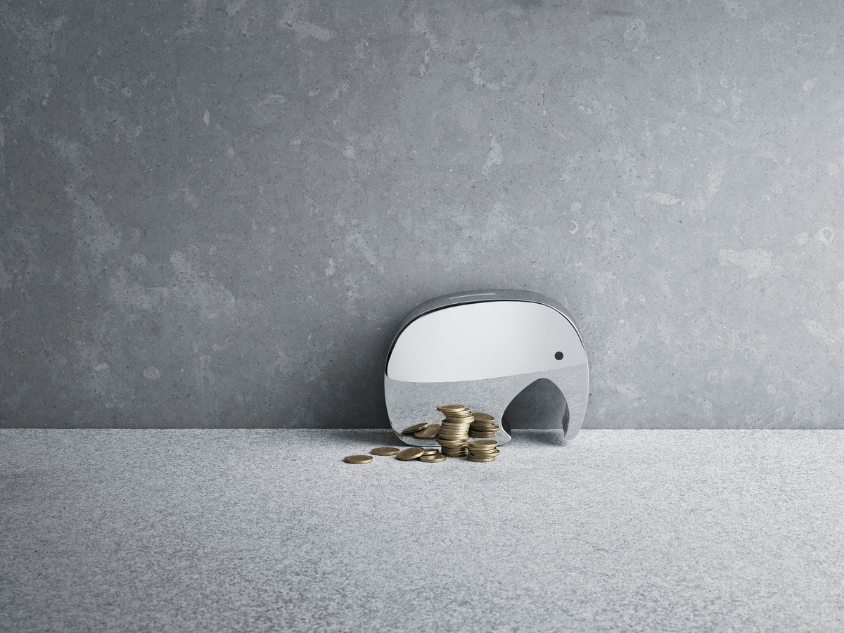 Side view of Moneyphant coin bank showcasing mirror polish stainless steel finish with coins on a gray stone surface