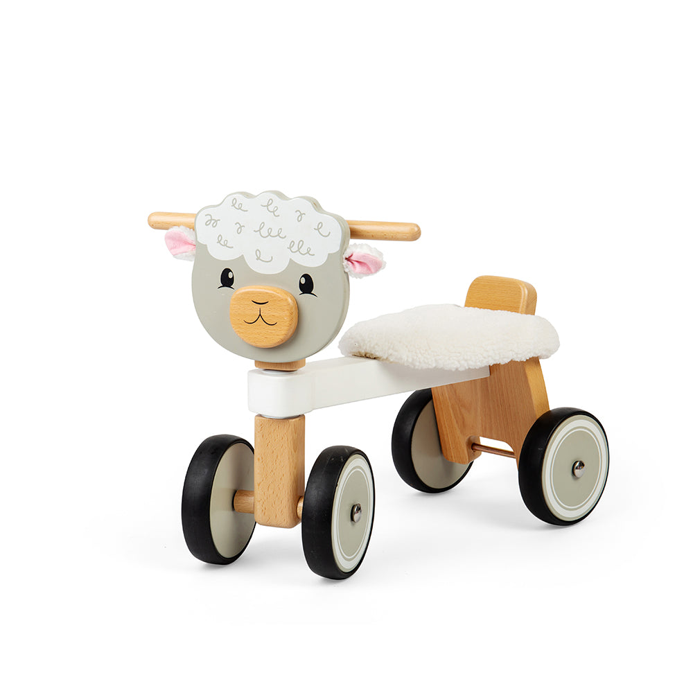 Front three-quarter view of Ride On Sheep showcasing four wheels, wooden handlebars, and fluffy seat on white background