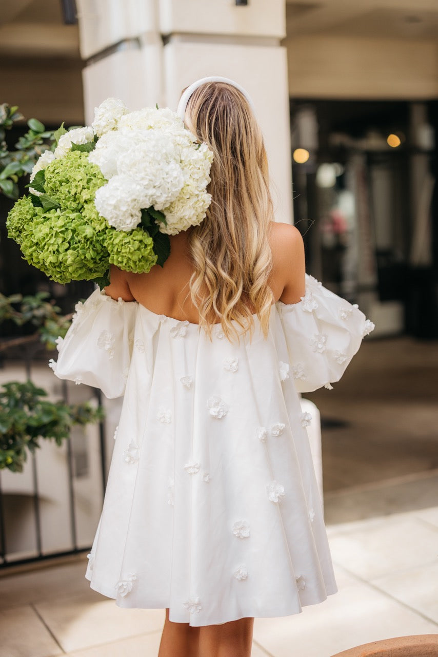 Back view of Posie Dress in ivory with off-the-shoulder puff sleeves and scattered 3D floral appliqués, short A-line skirt