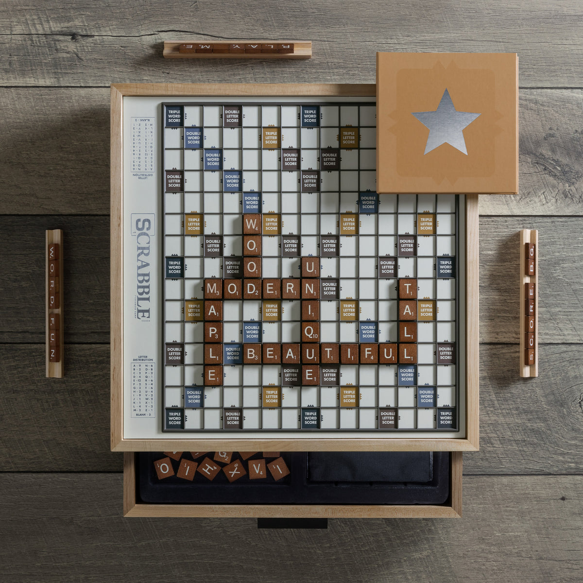 Top view of Scrabble Maple Luxe Edition showcasing rotating raised-letter board and solid maple cabinet on wood table