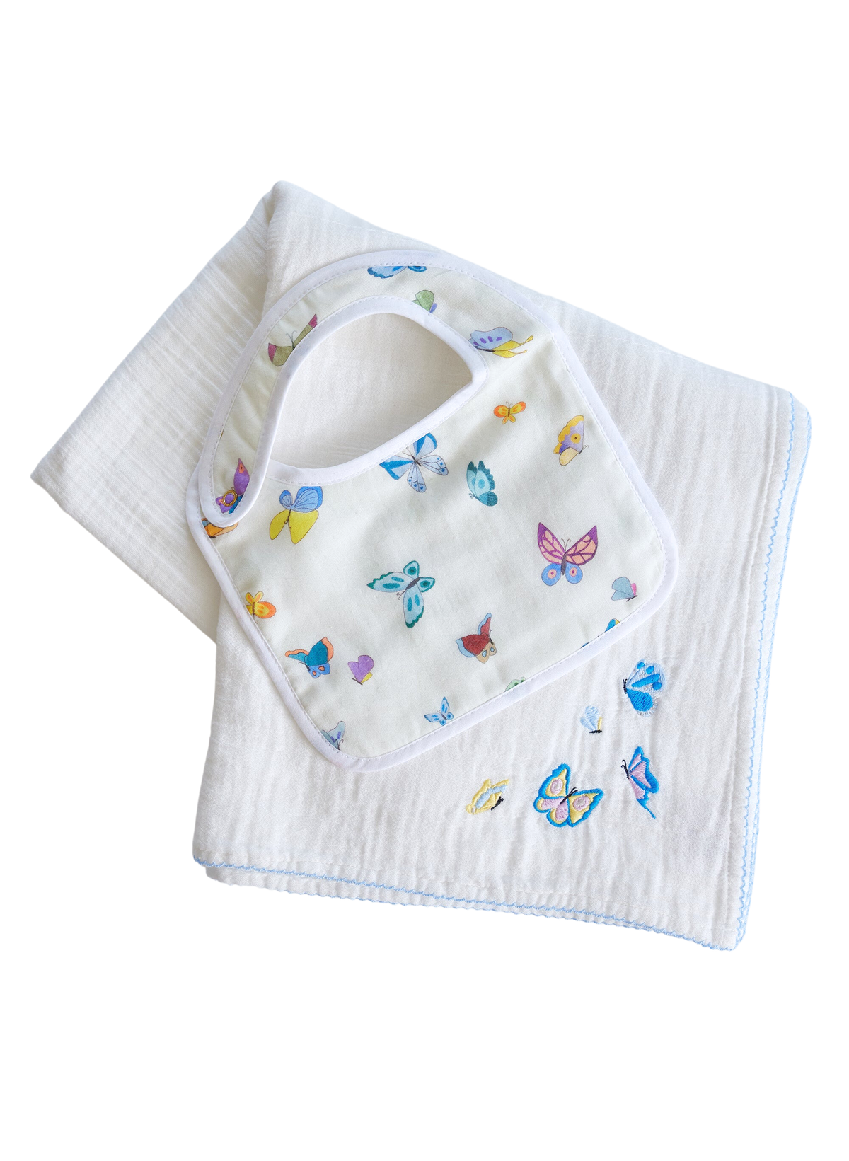 Angled view of Madame Butterfly bib and embroidered shawl blanket showing colorful butterflies on white fabric against a black background