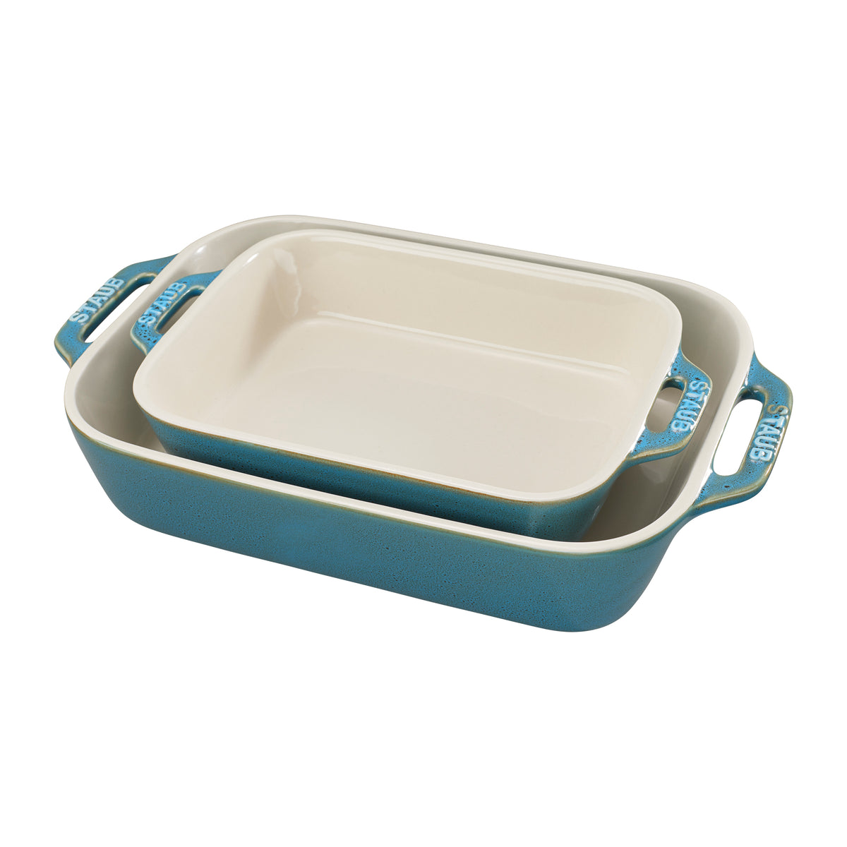 Angled view of Staub two-piece ceramic rectangular baking dish set showcasing rustic turquoise exteriors and cream interiors
