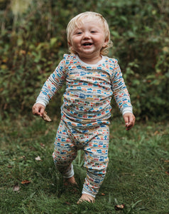 Front view of cars and trucks two-piece pajamas showcasing a colorful vehicle print on a smiling child outdoors