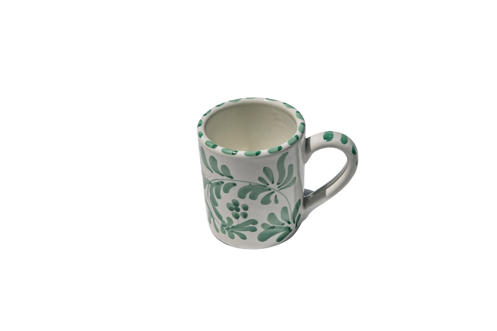 Angled front view of Americano mug showcasing green hand-painted leafy design on white ceramic with a plain black background