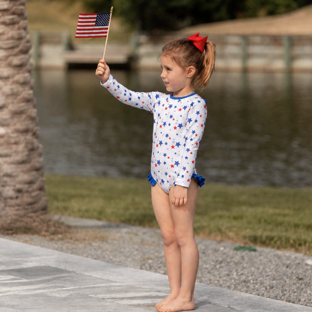 Henry Duvall Reese girls rashguard one piece in red white and blue star print, UPF 50+ long sleeve swimsuit for 4th of July, beach, and summer holidays