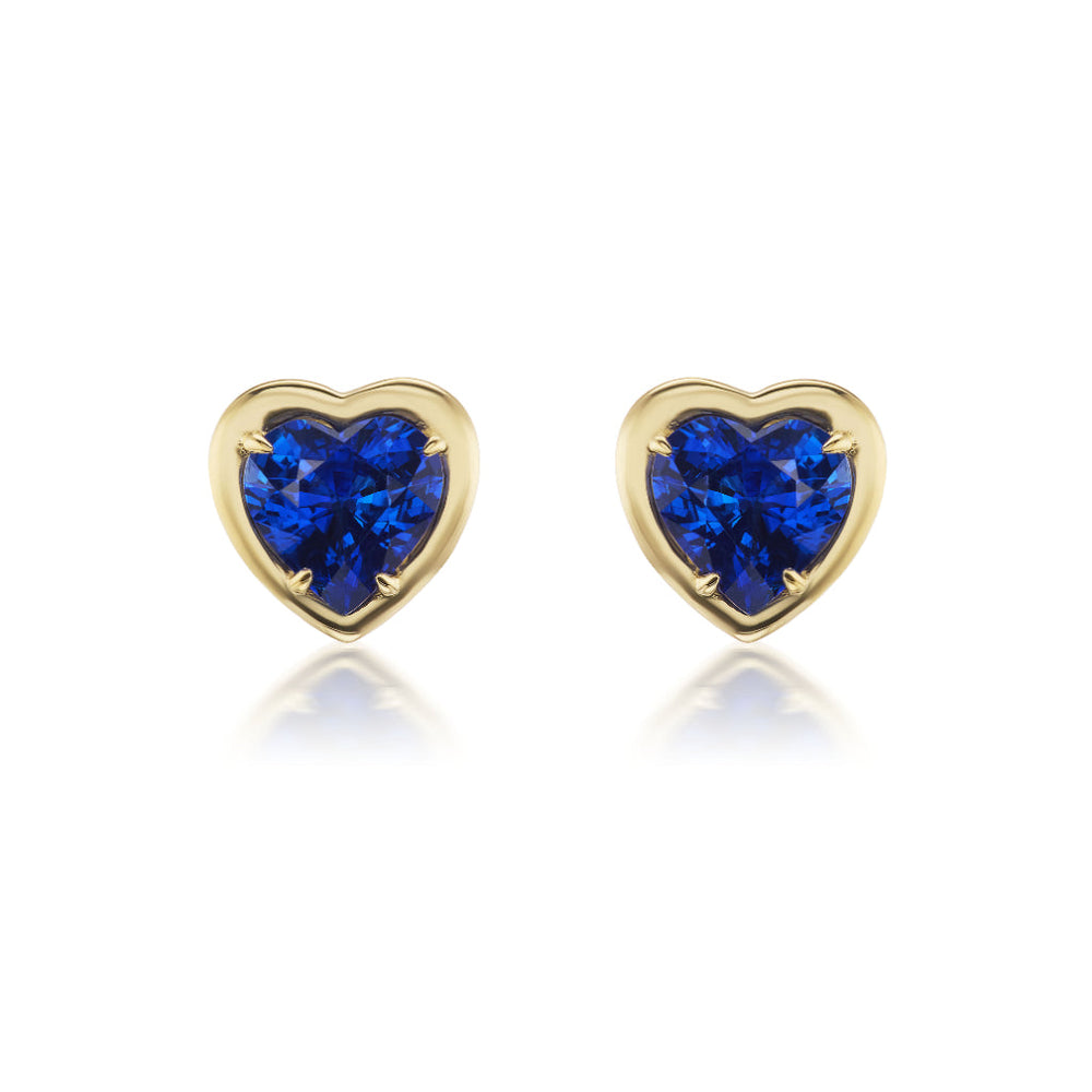 Blue Sapphire Heart Studs in Yellow Gold: Heart-shaped blue sapphires set in 18K yellow gold, these elegant studs are shown against a white background.