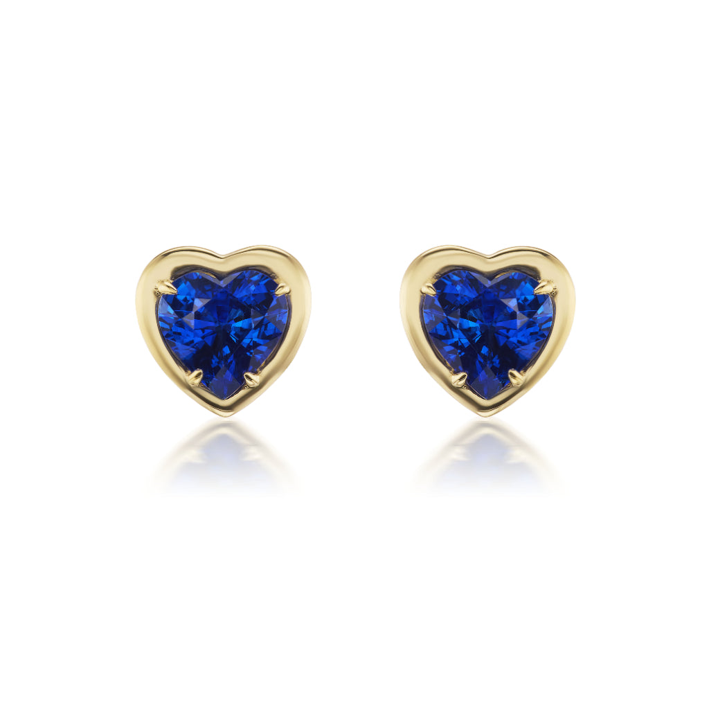 Blue Sapphire Heart Studs in Yellow Gold: Heart-shaped blue sapphires set in 18K yellow gold, these elegant studs are shown against a white background.