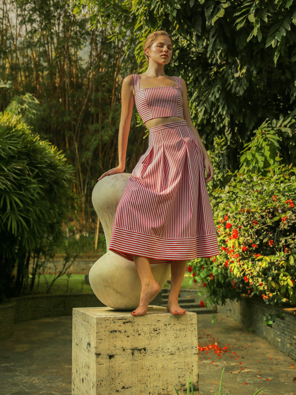 Front view of Vela skirt in red and white stripes showing high waist and full midi skirt on model in garden