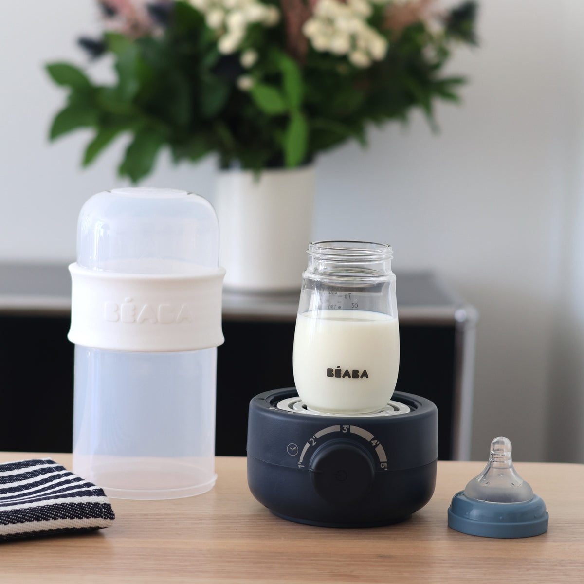 Front view of BabyMilk 3-In-1 Bottle Warmer in Midnight showcasing a bottle in the timer base with cover and nipple beside it
