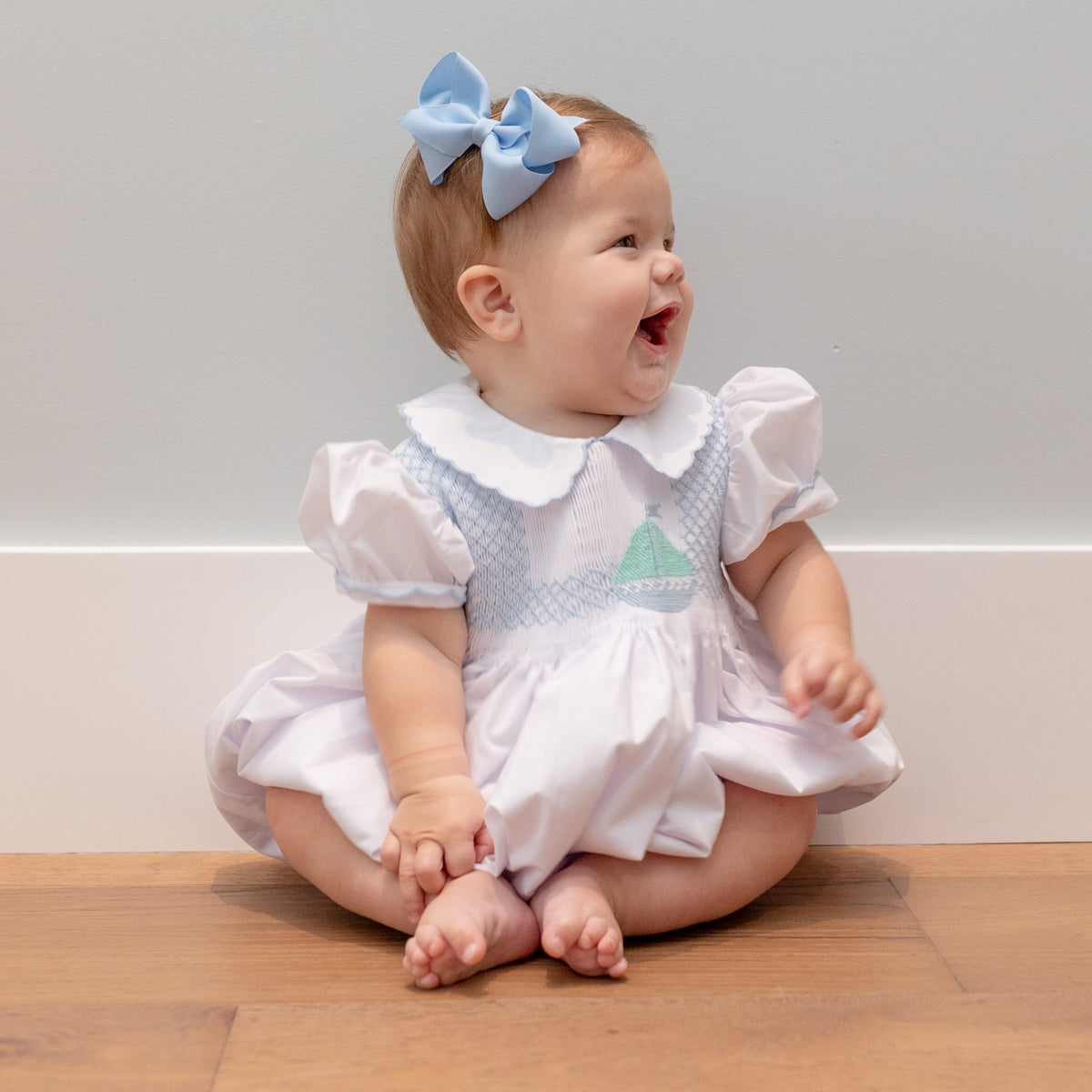 Henry Duvall Eloise Bubble in white cotton with Bailey’s Bay Blue trim and hand-smocked sailboats, classic heirloom baby girl summer outfit with scalloped Peter Pan collar