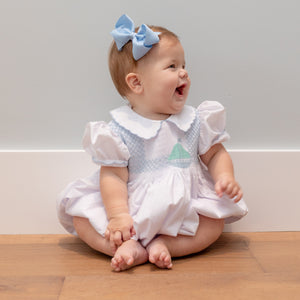 Henry Duvall Eloise Bubble in white cotton with Bailey’s Bay Blue trim and hand-smocked sailboats, classic heirloom baby girl summer outfit with scalloped Peter Pan collar