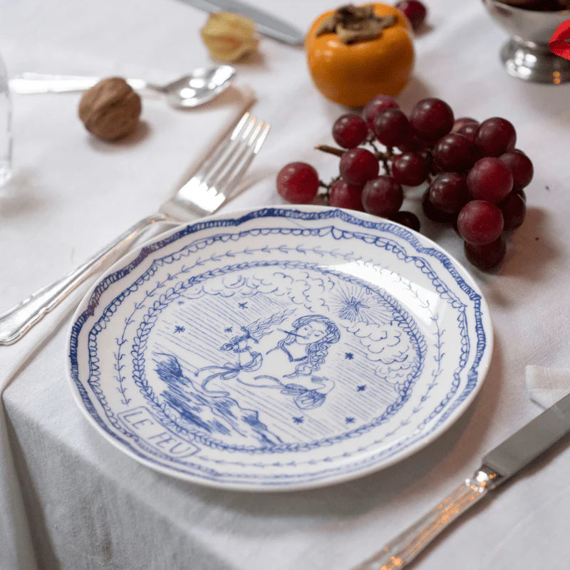 Angled view of Element ‘Le Feu’ plate with blue tarot illustration and ‘Le Feu’ label on a table with silverware