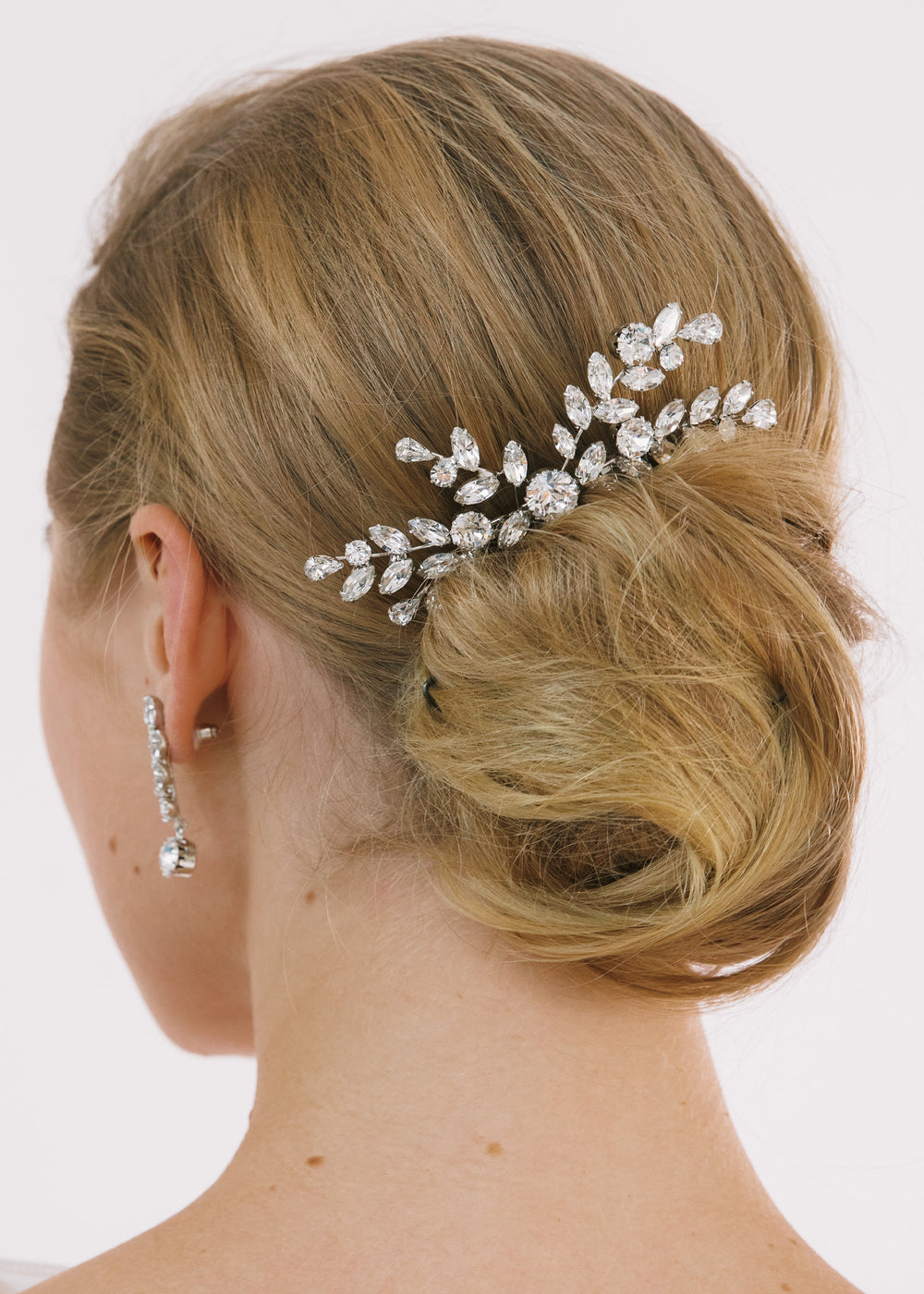 Rear view of Alessa comb in Crystal showing sparkling rhinestones in a leafy spray tucked into a low bun on pale background