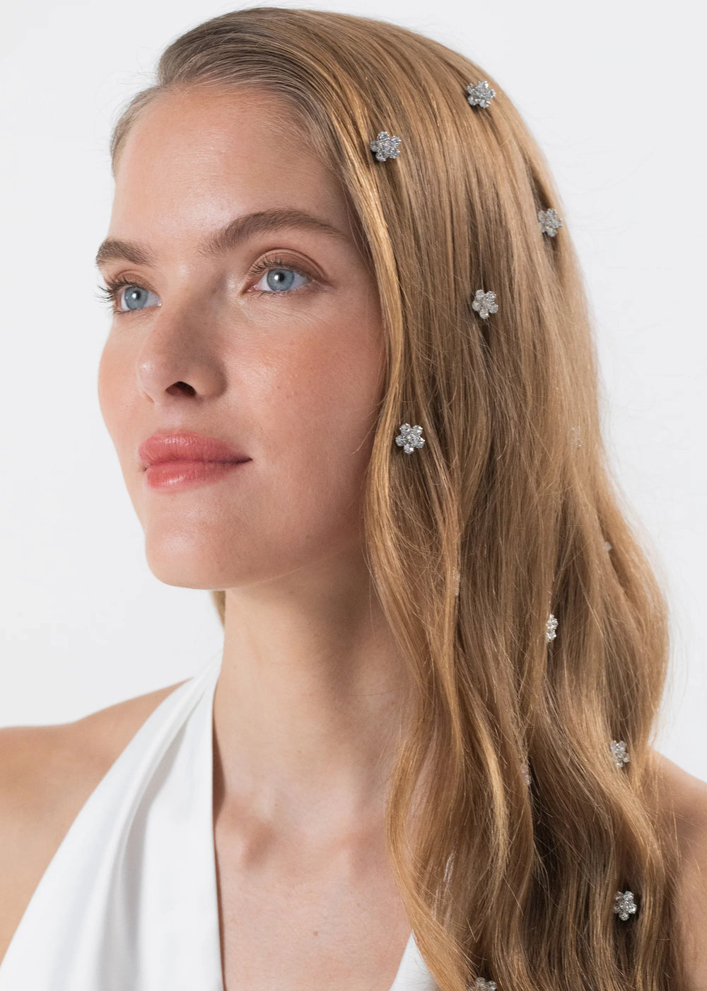 Three-quarter view of Violet Hair Magnets in Crystal showing floral crystal magnets scattered through long blonde hair