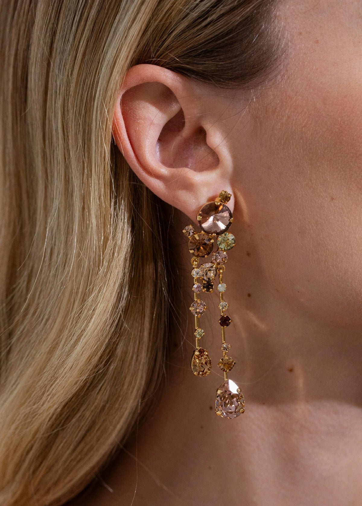 Close-up of Jayleen Earrings in Champagne showing cascading champagne-tone crystals and gold-plated setting on a model’s ear