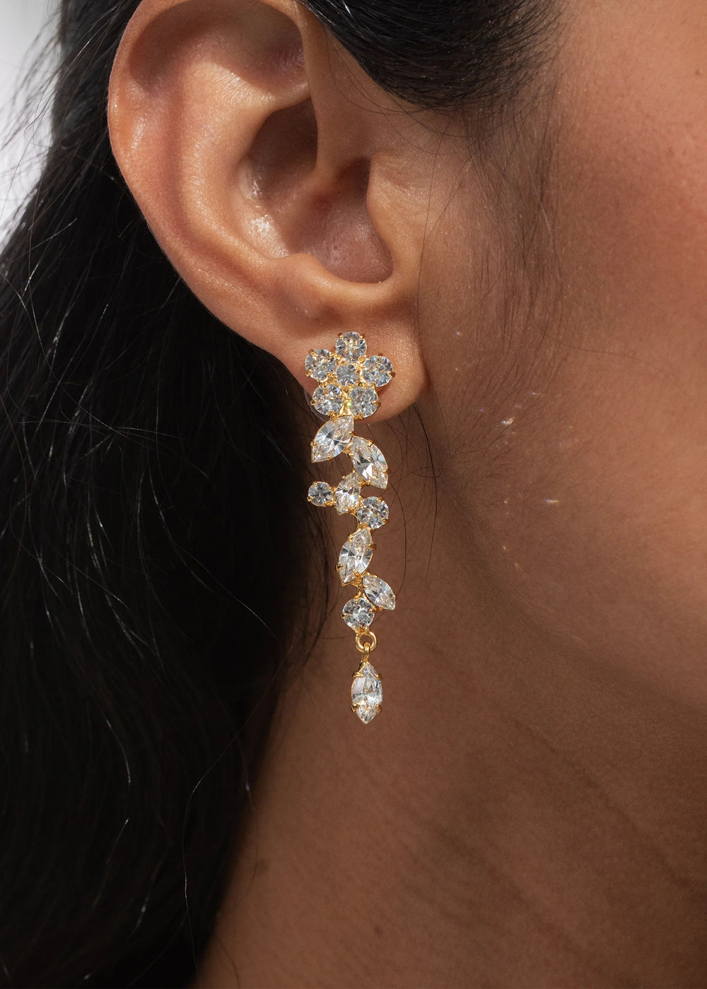 Side view of Jasmina earrings in Crystal Antique Gold showing floral drop of round and marquise crystals on model’s ear