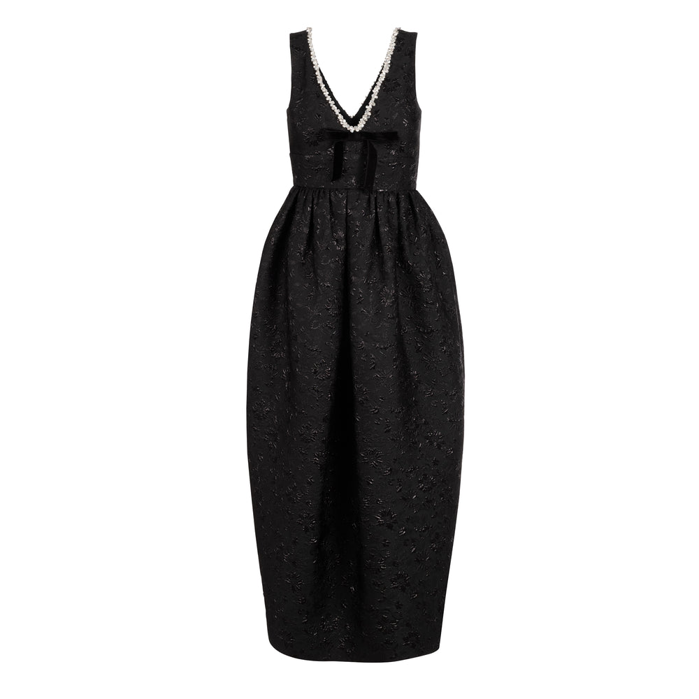 Front view of Rainey dress in black floral brocade showcasing deep V-neck with crystal trim, velvet bow at waist, and puffed tapered midi skirt on white background