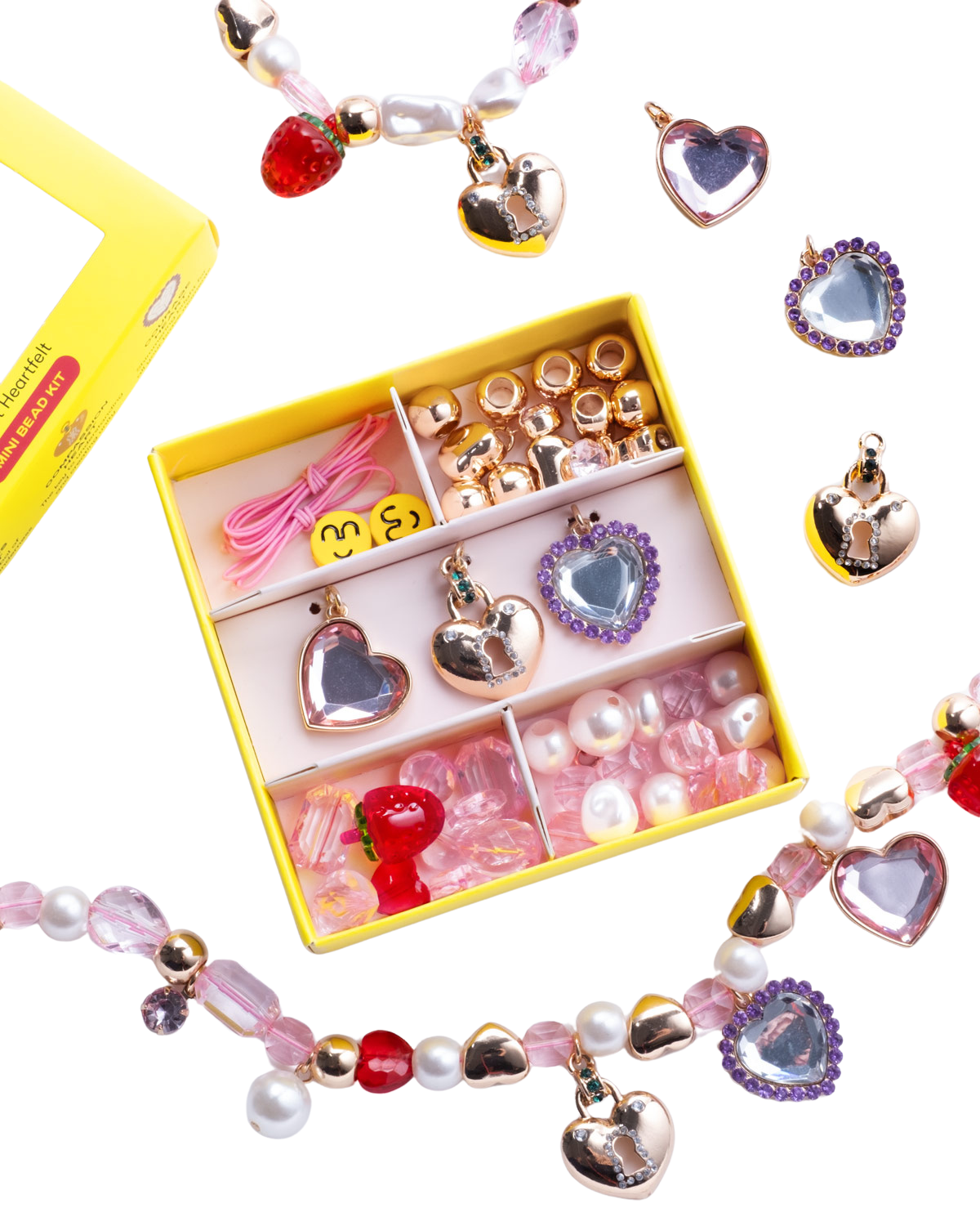 Top view of Make It Heartfelt Mini Bead Kit showcasing heart charms, pink beads, cords, and bracelets with black background