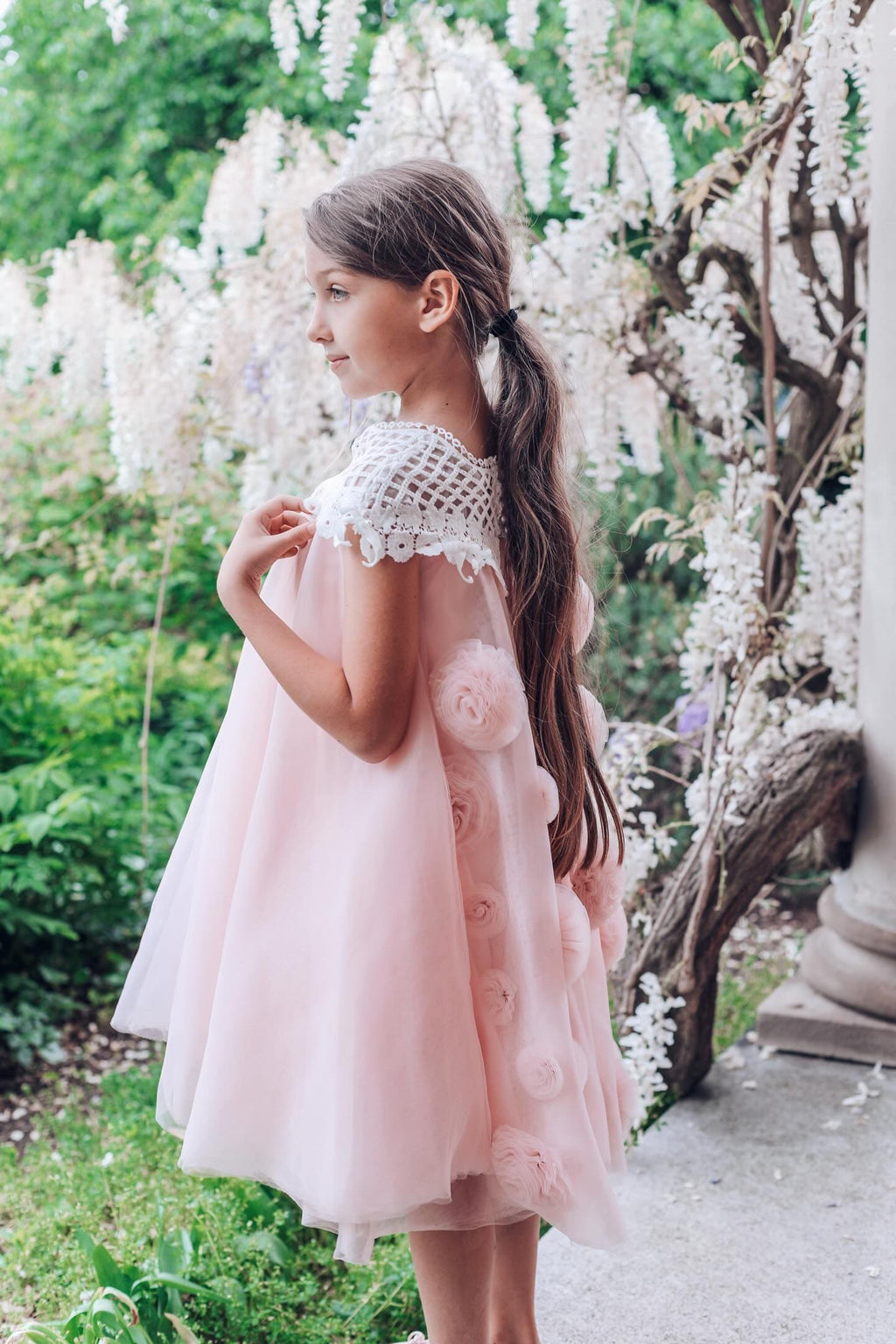 Side view of girls pink tulle dress with flower details styled for a special occasion 