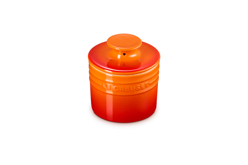 Three-quarter view of Le Creuset Butter Crock, 6 oz, showcasing the lid and embossed Le Creuset logo with flame orange-to-red glazed finish on a white background