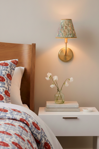 Lit hand-marbled clip-on sconce shade mounted on wall above bedside table