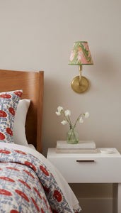 Wall-mounted sconce with hand-marbled clip-on lampshade in bedroom setting