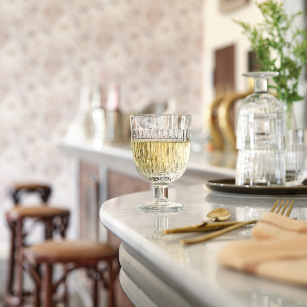 Front view of Ouessant stemmed wine glass showcasing ridged fluted bowl and short stem with white wine on marble countertop