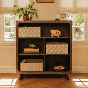 Front view of Astre Assembled Bookcase by Nate Berkus in Toffee with six compartments and rounded feet in a sunlit room
