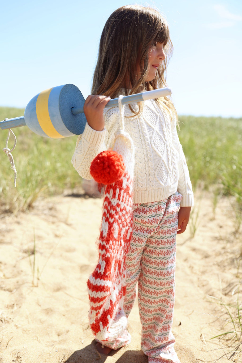 Side view of Christmas Lobsters Lounge Pants showcasing the red and green lobster print on a child outdoors by the beach