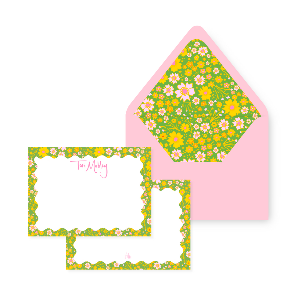 Angled view of Ditsy Floral stationery showing floral-bordered cards with pink handwritten name and matching pink envelopes