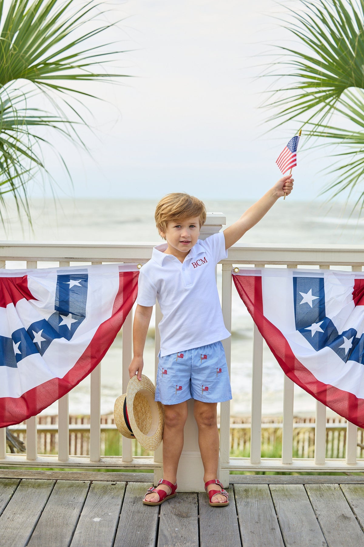Little English traditional children's clothing.  Blue gingham shorts with all-over American flag embroidery for boys.  Boy's shorts for 4th of July.