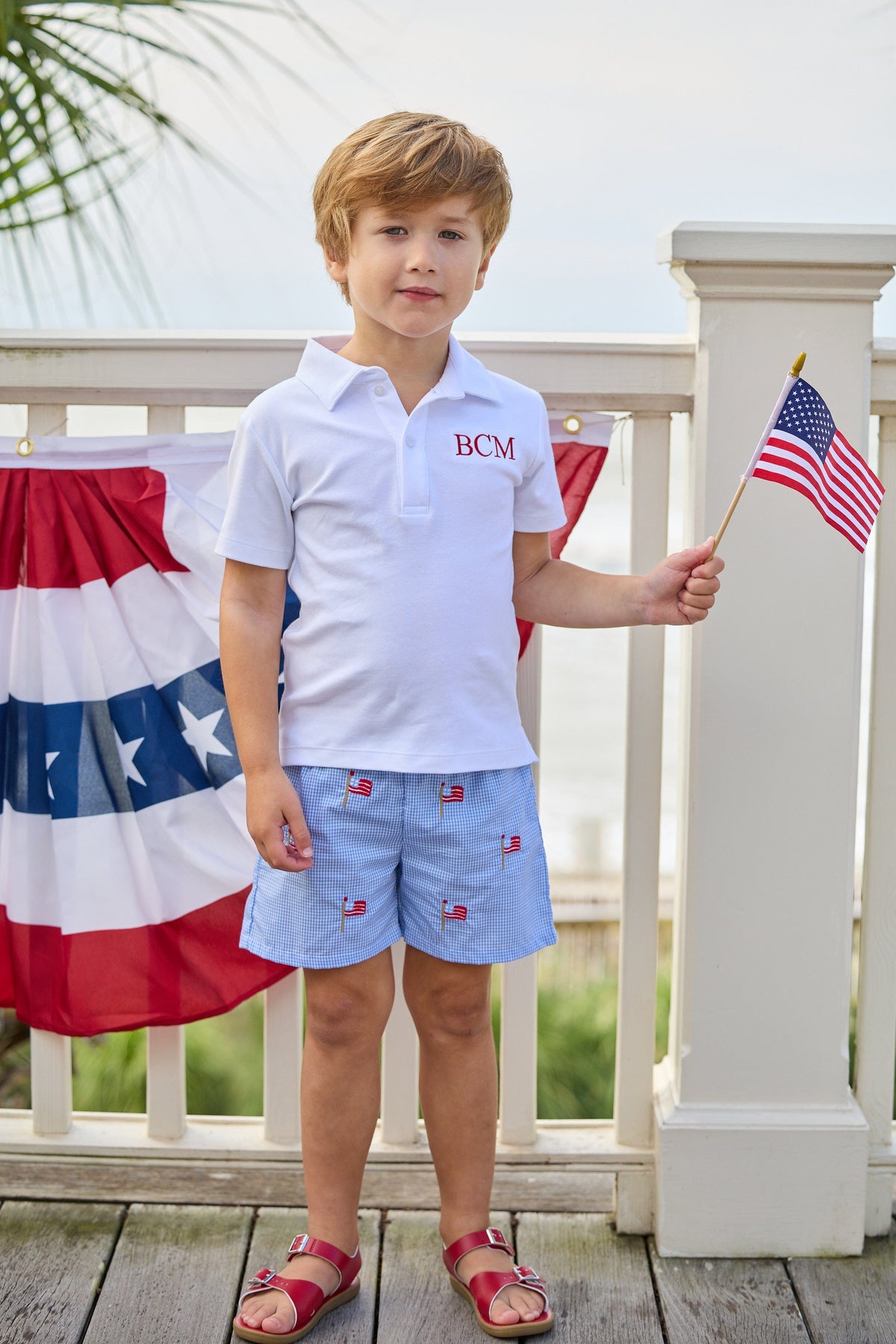 Little English traditional children's clothing.  Blue gingham shorts with all-over American flag embroidery for boys.  Boy's shorts for 4th of July.