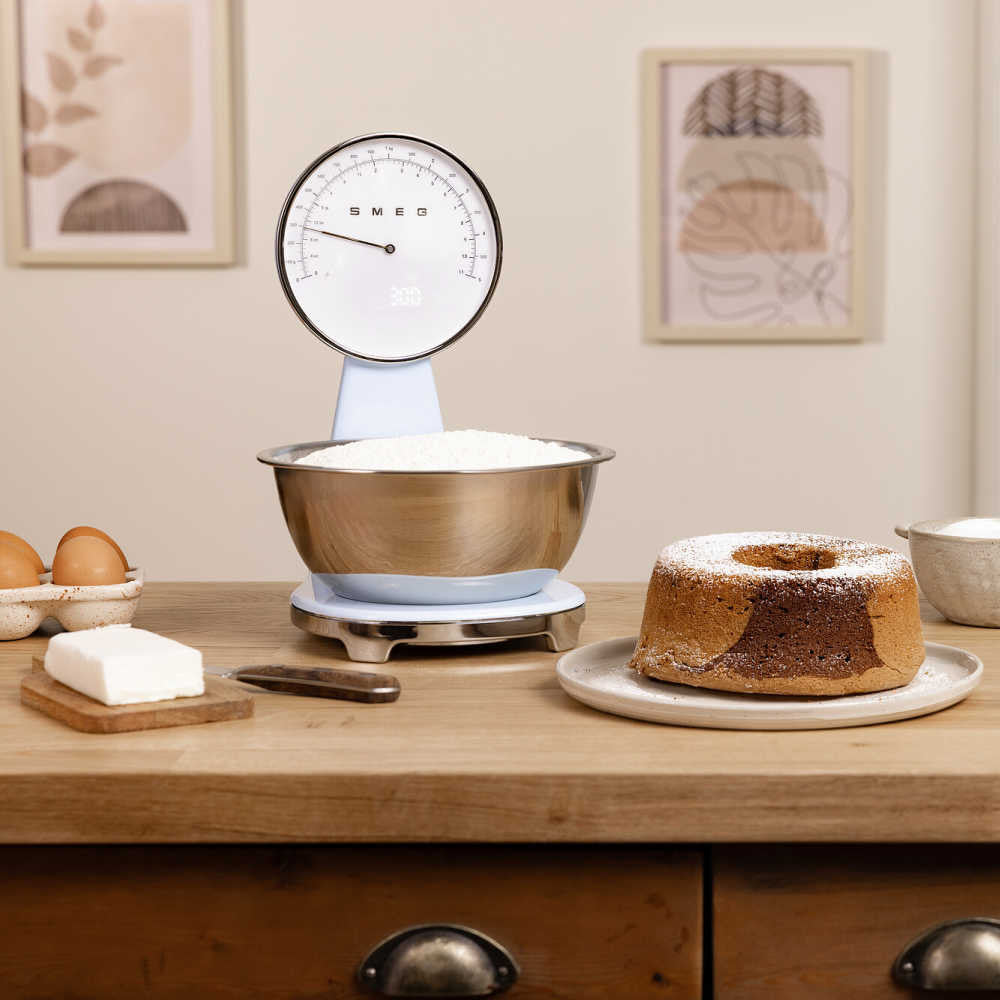 Front view of SMEG 50s kitchen scale with stainless steel bowl and analog dial with digital display on countertop