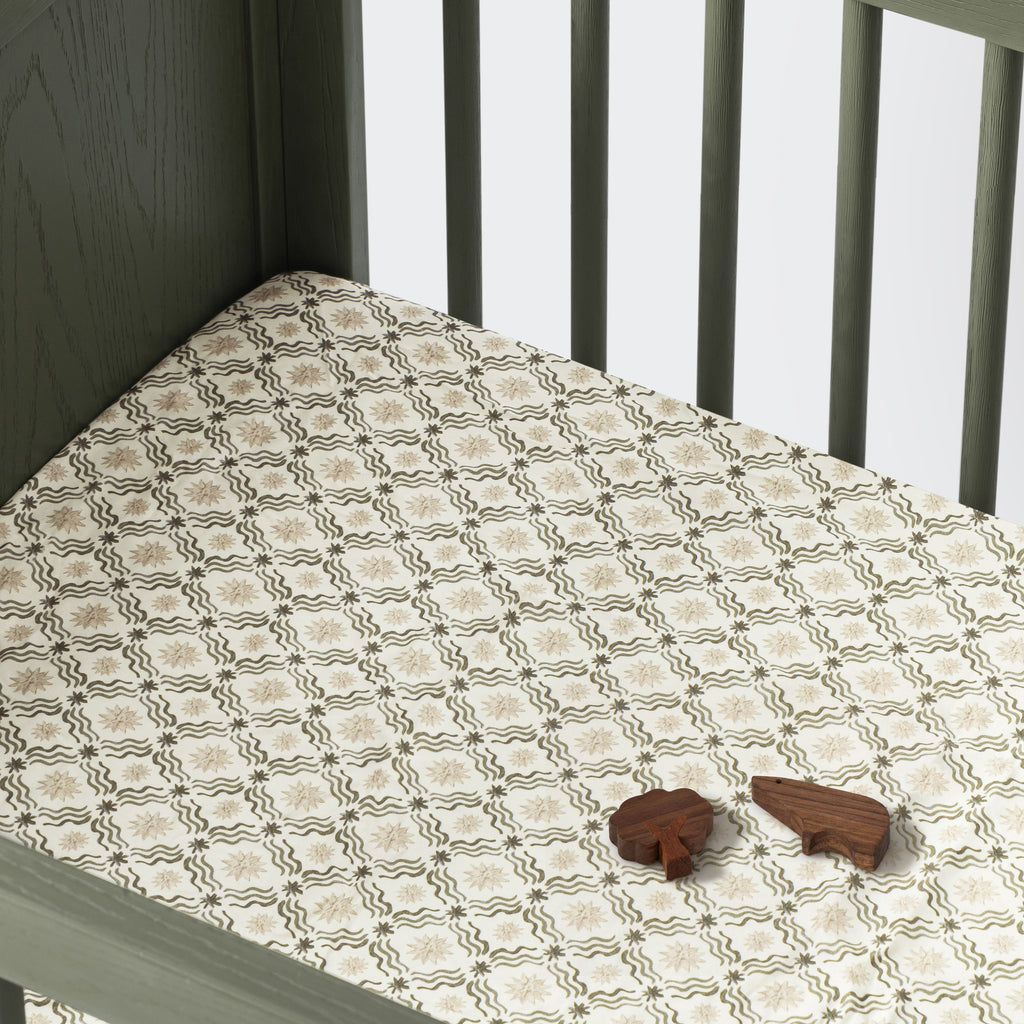Angled view of All-Stages Midi Crib Sheet showcasing Juniper Star pattern fitted on a crib mattress with white rails