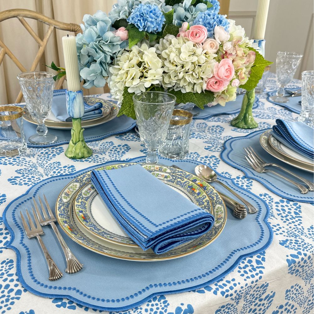 Elegant table setting with floral centerpiece, blue and white tablecloth, and silverware.