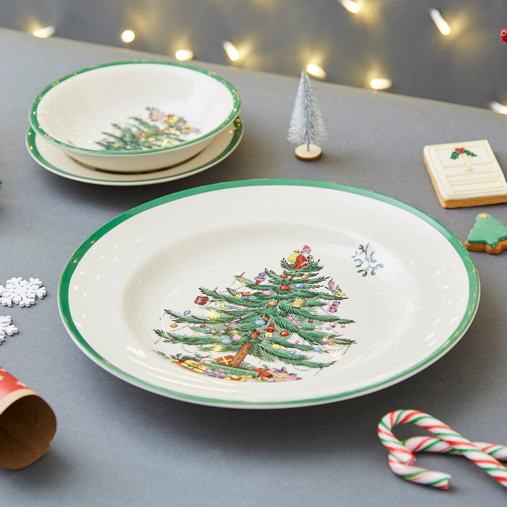 Close-up of 10.5-inch Christmas Tree dinner plate showing tree motif and green rim on gray tabletop with cookies