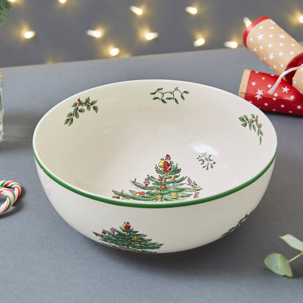 Angled top-down view of 10-inch Spode Christmas Tree large round bowl showcasing tree motif and green rim on gray tabletop