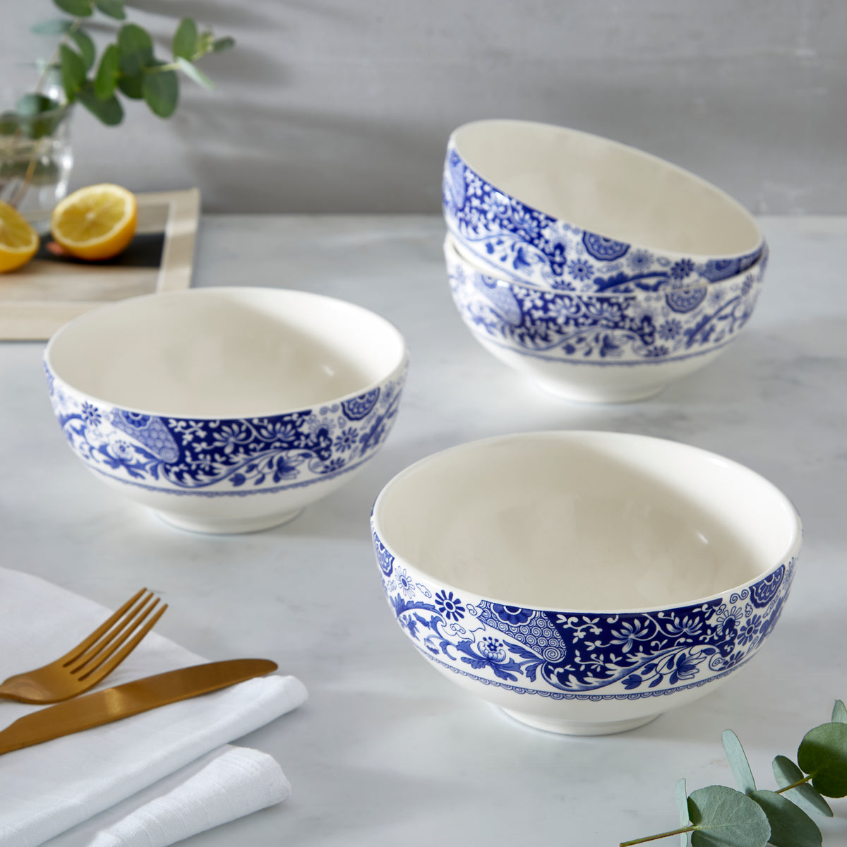 Close-up of Brocato 6.5 inch bowls, set of 4 showcasing white porcelain with scroll and floral design on a table setting