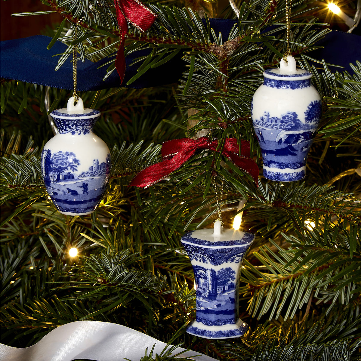 Close-up of Blue Italian Christmas Mini Urn Ornaments, Set of 3, showcasing blue and white scenic pattern on an evergreen tree