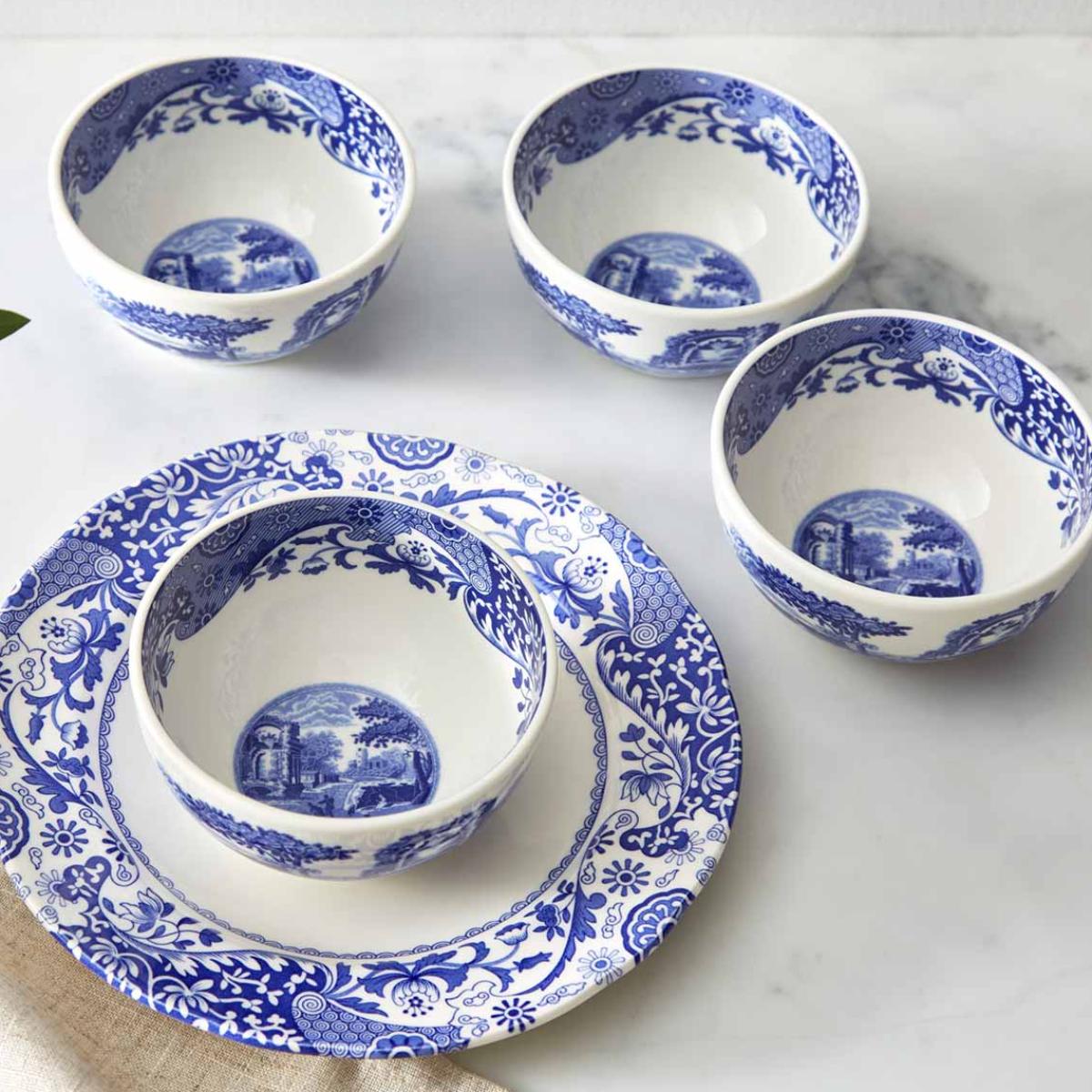 Angled view of Blue Italian Dip Bowls, Set of 4 showcasing blue-and-white countryside patterns on a marble surface