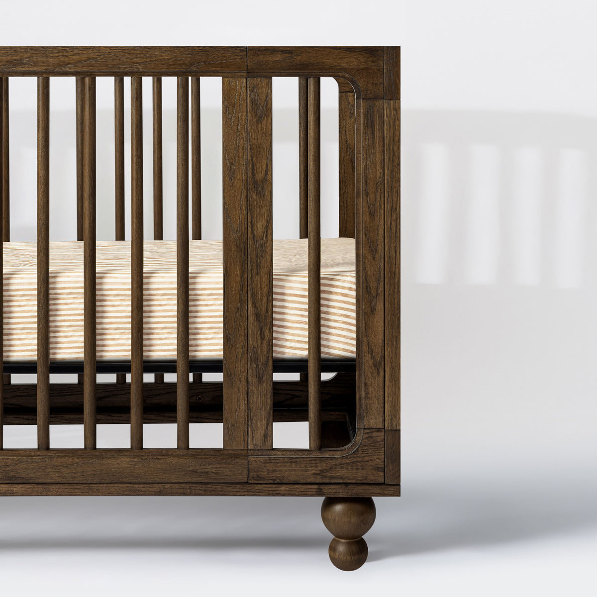 Close-up of Nate Berkus Autumn Stripe crib sheet in GOTS certified organic brushed cotton, shown in a dark wood crib