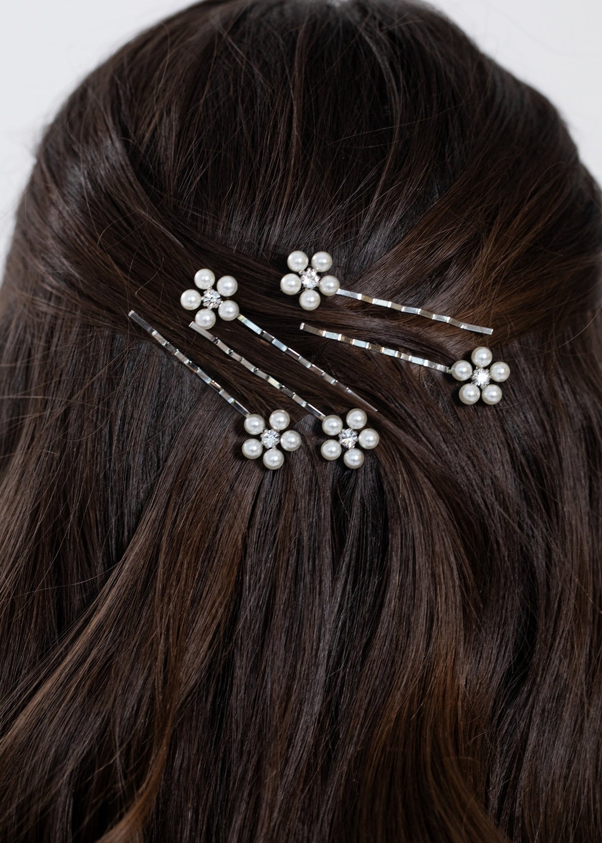 Close-up of Zaya Bobby Pin Set in Silver showcasing five pearl daisies with crystal centers in dark brown hair