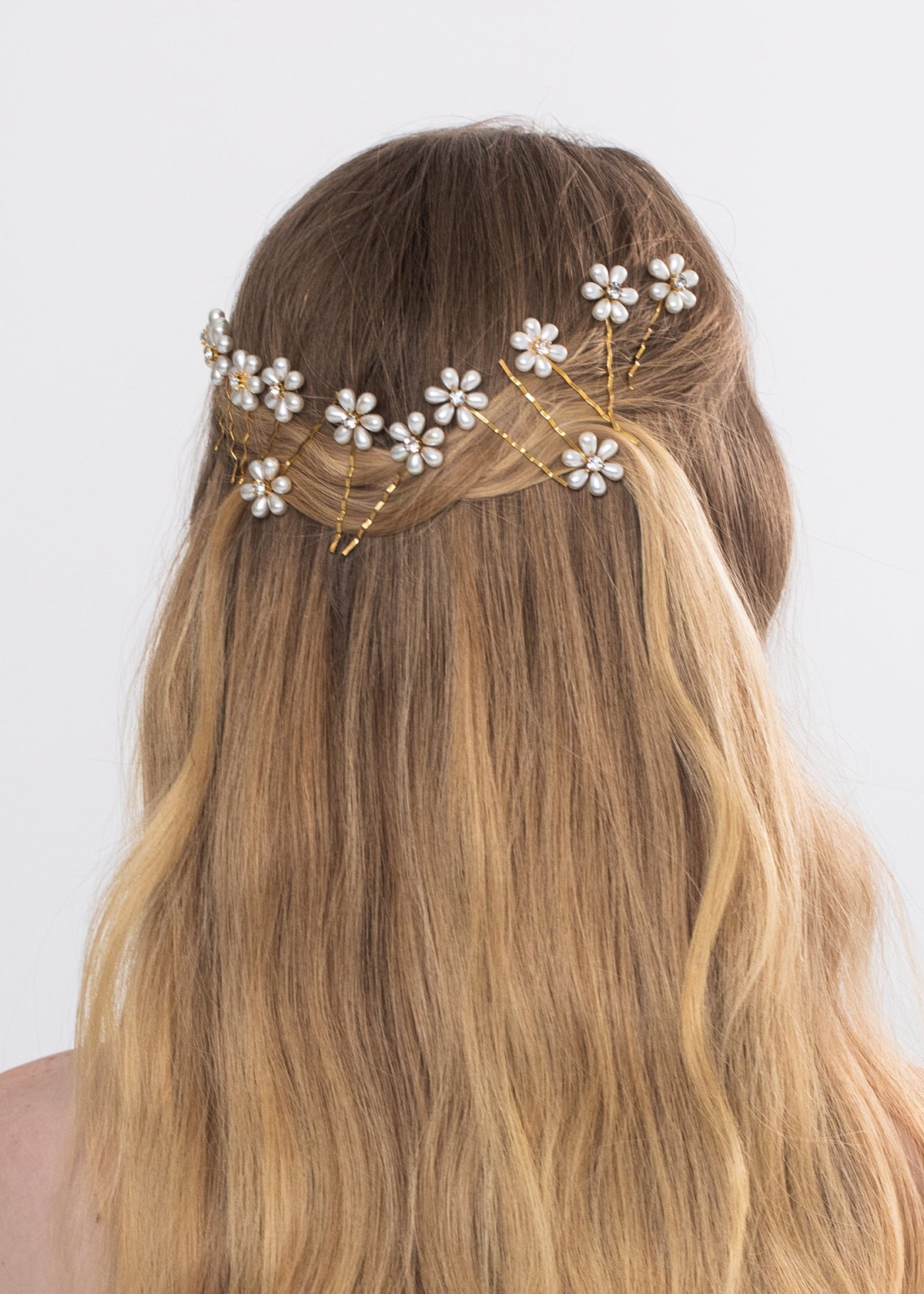 Back view of the Laena Bobby Pin Set in Gold showcasing pearl flower details styled in brown hair against a white background