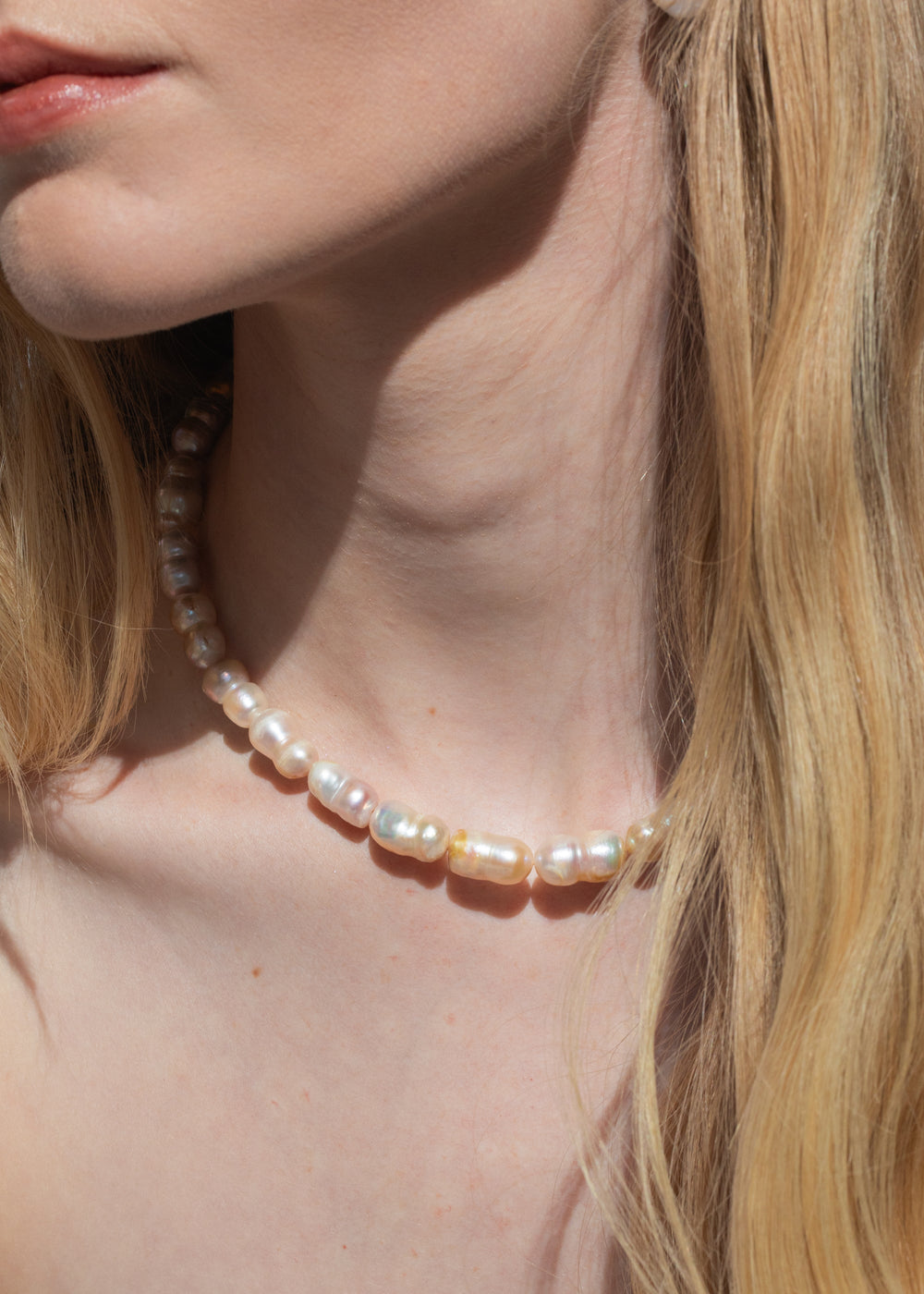 Close-up of model wearing Lilah Necklace in Pearl showing warm champagne freshwater baroque pearls on bare neck