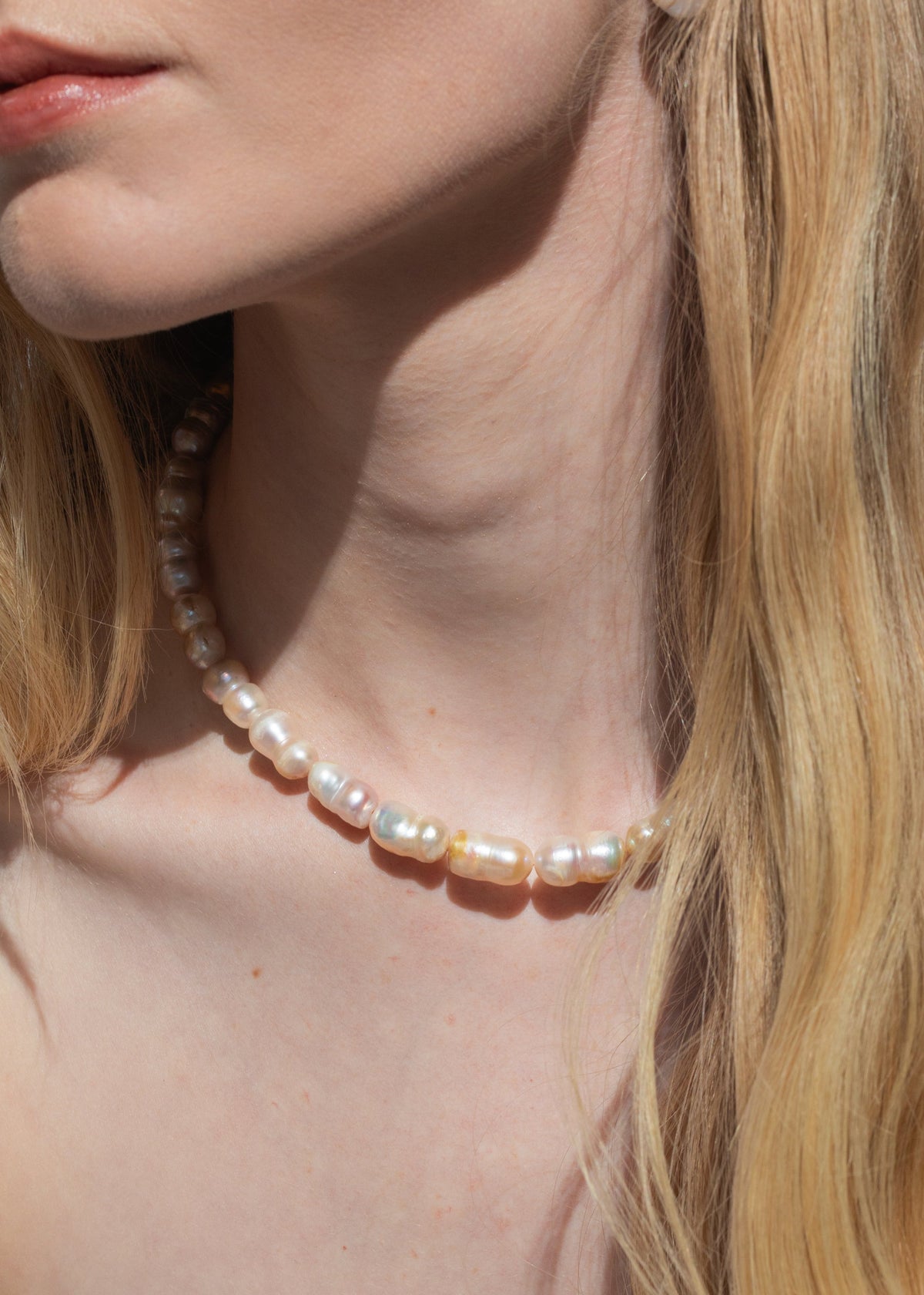Close-up of model wearing Lilah Necklace in Pearl showing warm champagne freshwater baroque pearls on bare neck
