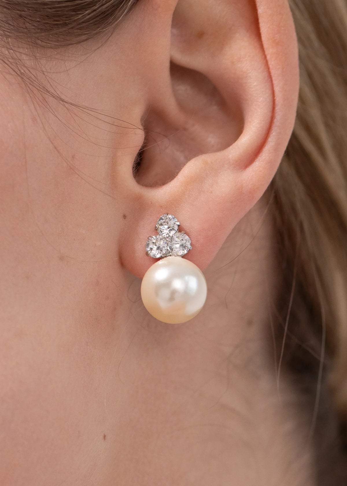 Close-up side view of Belen earrings in crystal showing three Austrian crystals above a crystal pearl drop on an ear