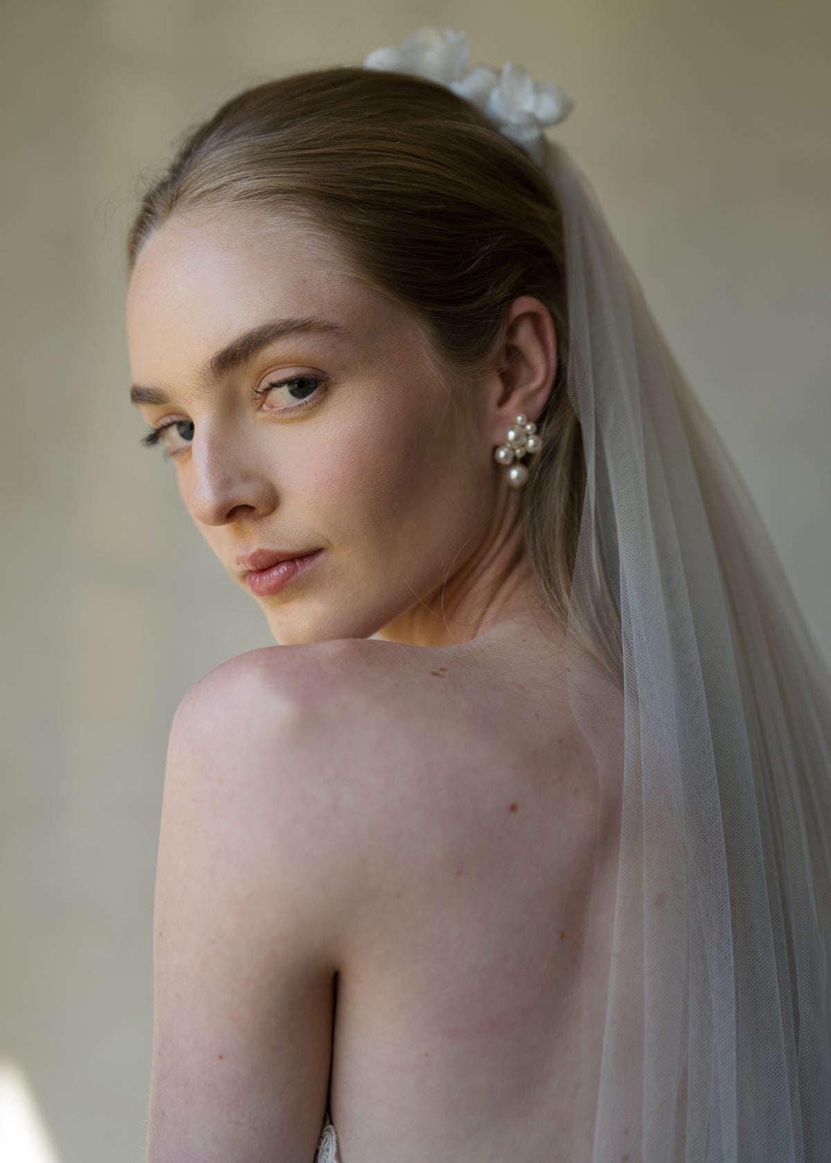 Bride wearing Perlita pearl drop earrings with a veil in a close-up portrait