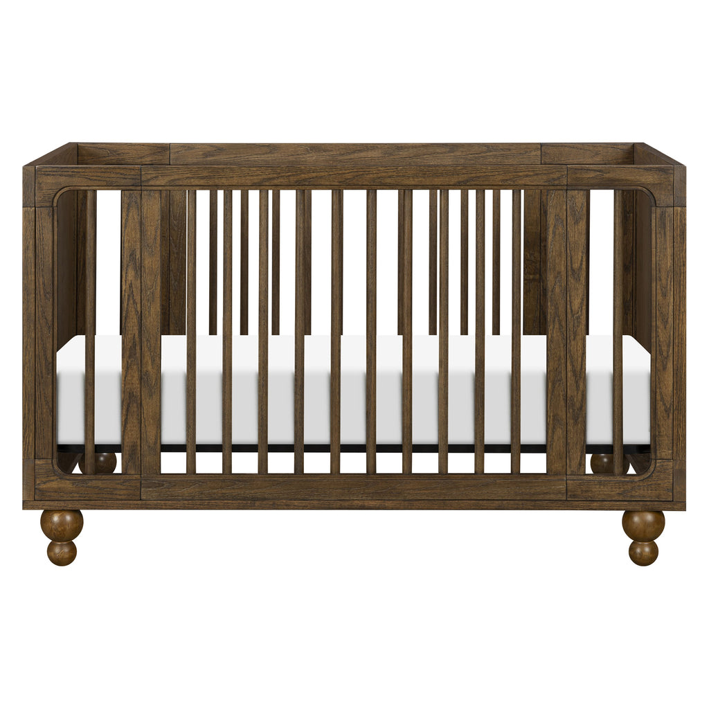Front view of Astre All-Stages 8-in-1 crib in Toffee showcasing vertical slats and rounded feet on a white background
